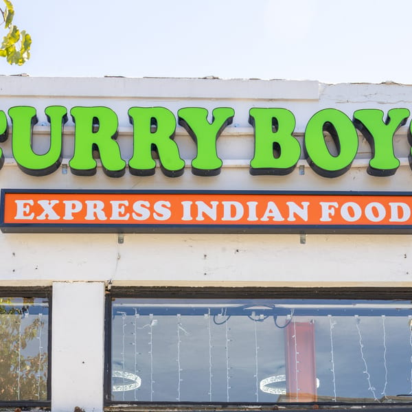 Curry Boys Express Indian Food restaurant sign with bright green letters and an orange banner.